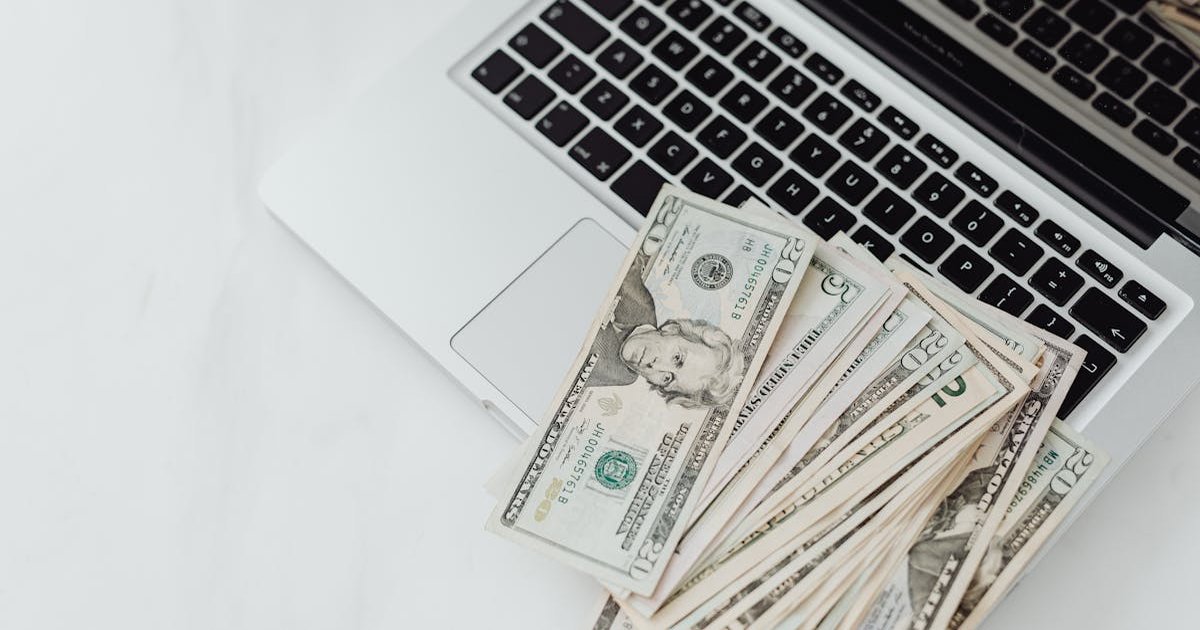 Freelancer reviewing bank account options on a laptop with financial charts visible